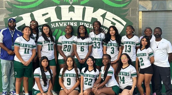 The Girls' Flag Football team posing in front of one of Hawkins' murals.