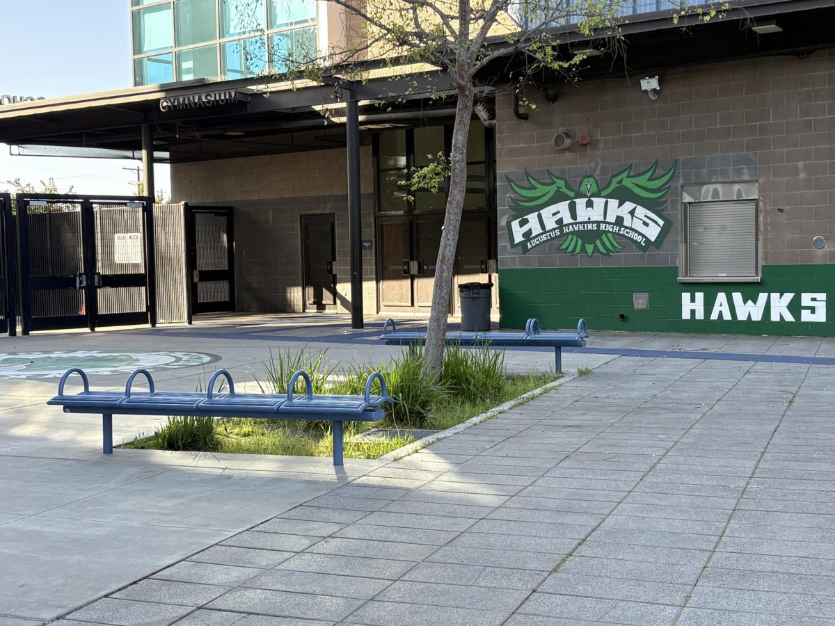 The entrance courtyard at Augustus F. Hawkins High School features the campus “Hawks Pride” mural as afternoon light shines across the open student area. 